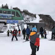 Quelques skieurs attendent en file pour monter dans le télésiège.