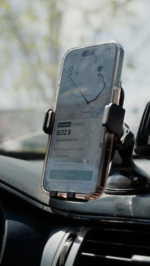 Un téléphone cellulaire fixé au tableau de bord d’une voiture affiche un itinéraire de navigation pendant une livraison.