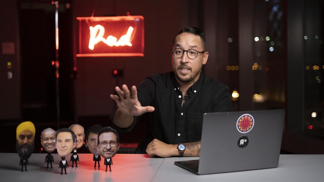 Le journaliste Nicolas Pham parle derrière un bureau.